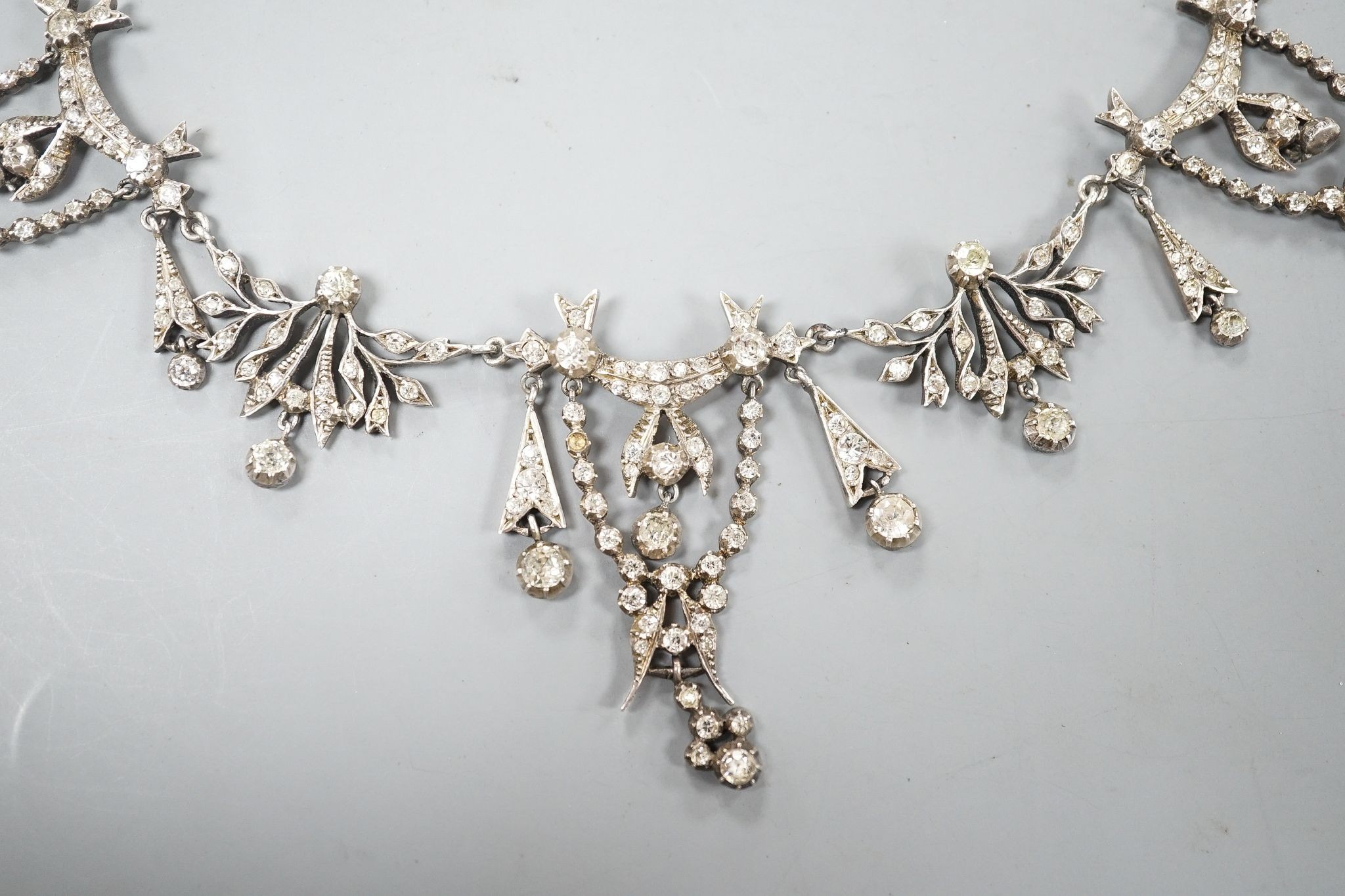 A 19th century white metal and paste set drop necklace, 37.5cm, in an associated gilt tooled fitted leather box.